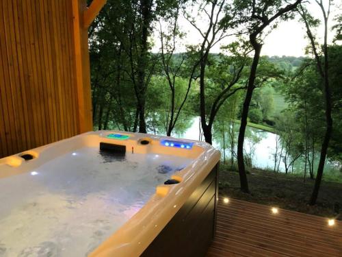 a bath tub with a view of a river at Les Cabanes du Lac - SPA - Petit Déjeuné - Cabane du frêne & Cabane du chêne Premium in Sévignac-Thèze