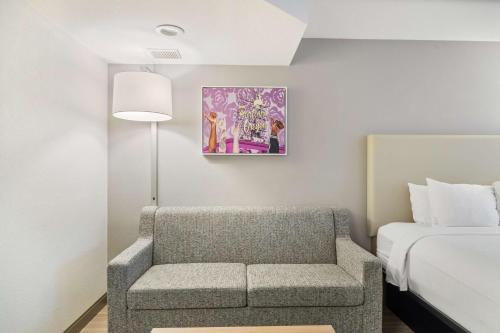a room with a chair and a bed and a painting at Best Western Lake Oswego Hotel & Suites in Lake Oswego