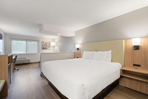 a bedroom with a large white bed and a desk at Best Western Lake Oswego Hotel & Suites in Lake Oswego