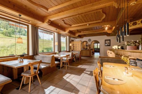 a restaurant with wooden ceilings and tables and windows at Pension Schneerose - Wildschönau - PREMIUM CARD im Sommer in Wildschönau