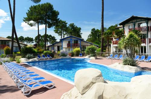 a swimming pool with lounge chairs and a resort at Résidence Odalys Les Greens du Bassin in Gujan-Mestras
