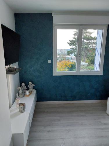 La salle de bains est pourvue d'un mur bleu et d'une fenêtre. dans l'établissement La détente 2 etoiles, à Sangatte