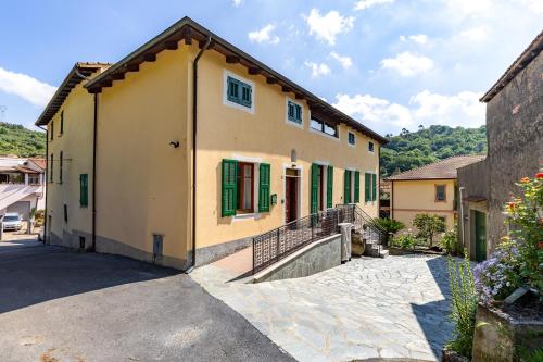 a yellow house with green shutters and a staircase at Hostdomus-Country House in Orco Feglino