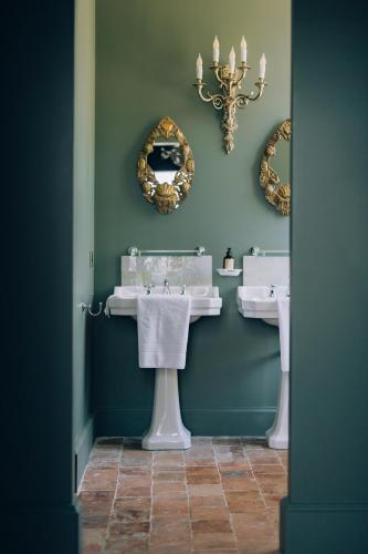 une salle de bain avec deux lavabos et deux miroirs dans l'établissement 16th century Norman Manor, à Troarn