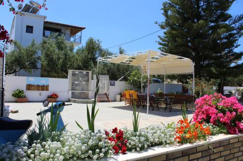 a patio with a bunch of flowers and an umbrella at Panorama Studios & Apartments in Amoudi