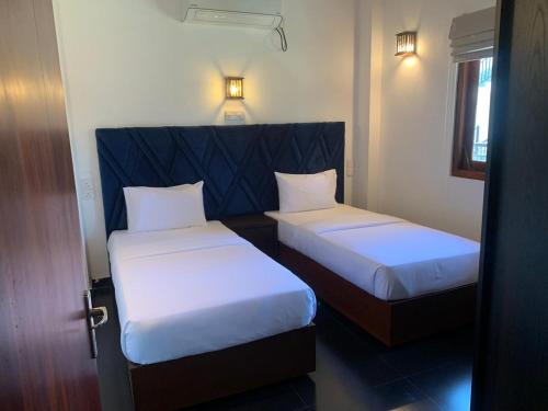 two beds in a hotel room with a door open at Grand Leisure Care & Wellness Resort in Negombo