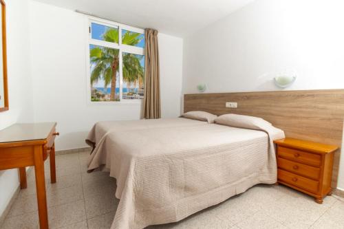 a bedroom with a bed and a window at Apartamentos Tamaragua in Playa del Ingles