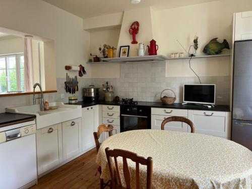 une cuisine avec des armoires blanches et une table avec des chaises dans l'établissement maison proche bourg et plages 7 personnes jardin Ker Emmanuel, à Erquy