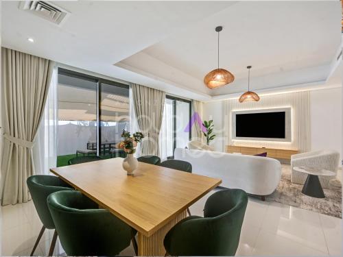 a living room with a dining table and a couch at 4BR Luxurious Villa DAMAC Hills 2 in Dubai