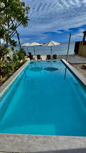 a blue swimming pool with a view of the ocean at Southseas Beach Resort and Dive Center in Santander