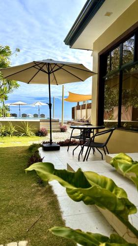 a patio with a table and chairs and an umbrella at Southseas Beach Resort and Dive Center in Santander