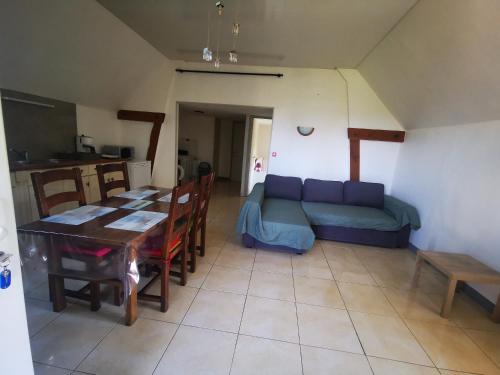 un salon avec un canapé bleu et une table dans l'établissement Les grands pins, à Fiquefleur-Équainville