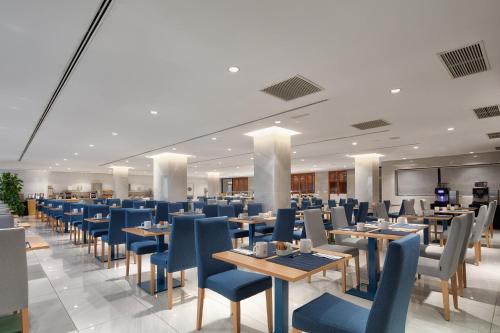 a dining room with tables and blue chairs at Eurostars Puerto de Ibiza in Ibiza Town