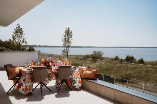 a table and chairs on a balcony with a view of the water at luxuriöse Villa Möwengeflüster - 220qm große Ferienwohnung für bis zu 8 Gästen mit Sauna direkt am Goitzschesee in Pouch