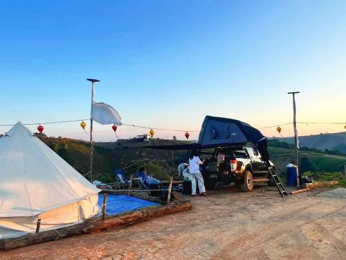 a group of people standing next to a tent at Wisdom Hill Campground in Phop Phra