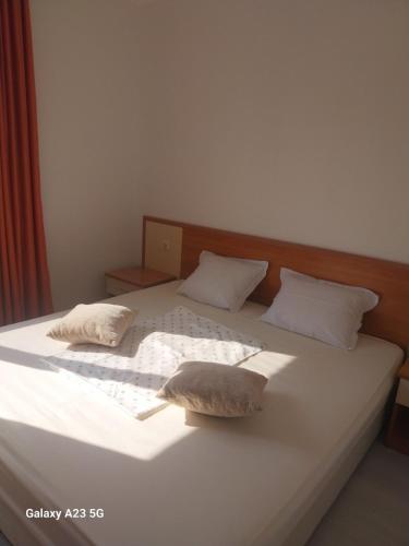 ein großes weißes Bett mit zwei Kissen darauf in der Unterkunft Апартамент Бяла in Byala