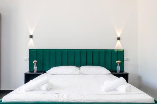 a white bed with a green headboard and two tables at ALLIANCE Hotel NEW 2025 -Breakfast and pool included in Solotvyno