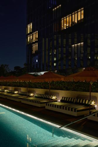 a row of umbrellas next to a swimming pool at night at The Standard, Singapore in Singapore