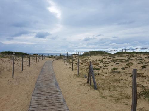 un chemin en bois traversant le sable sur une plage dans l'établissement Appart à Seignosse Le Penon, à Seignosse