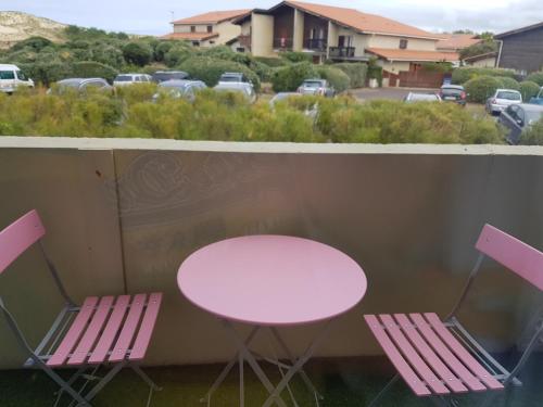 2 chaises roses, une table et une table avec des chaises dans l'établissement Appart à Seignosse Le Penon, à Seignosse