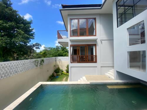 a house with a swimming pool in front of a house at SummerVille Nusa Dua by REJA Villas in Nusa Dua