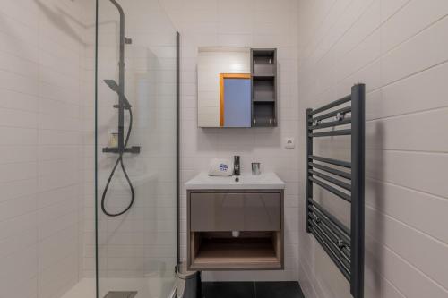une salle de bain blanche avec un lavabo et une douche dans l'établissement Tavaillons Apartment - Snow and Trek- Morzine, à Morzine