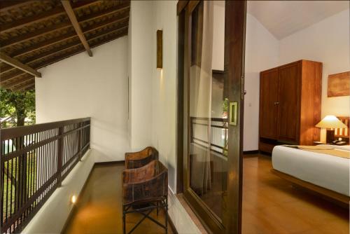 a room with a balcony with a bed and a chair at SigiriyaJungles Resort & Spa in Sigiriya