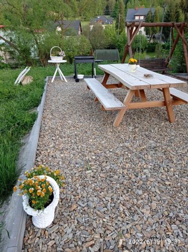 a picnic table and a bench on a gravel patio at Domek nad Potokiem in Szczytna