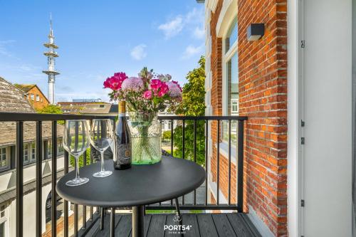 a table with two wine glasses and flowers on a balcony at Maybach Suite Westerland auf Sylt in Westerland