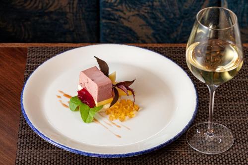 a white plate with a dessert and a glass of wine at Chateau Loucen Garden Retreat in Loučeň
