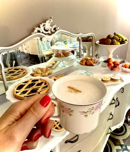 a person holding a cup on a table with food at Villa La Dogana B&B di Charme - Historic Villa with a beautiful garden - private parking in Lucca