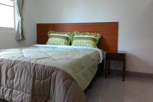 a bedroom with a large bed with a wooden headboard at M Place Maerim in Chiang Mai