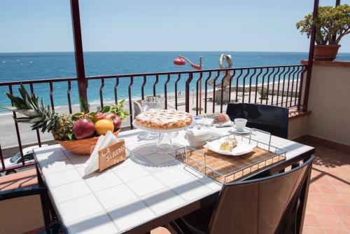 a table on a balcony with a view of the ocean at B&B La Sirena in Santa Teresa di Riva