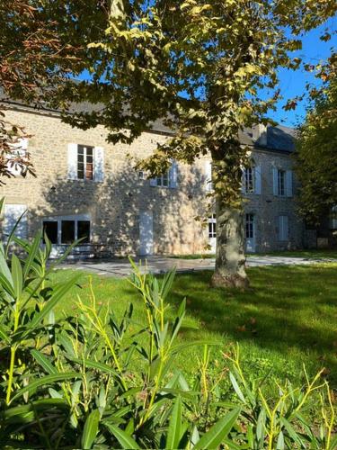 un grand bâtiment en briques avec un arbre dans la cour dans l'établissement Belle résidence de vacances en plein cœur d'Alvignac, à Alvignac