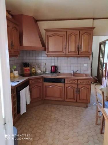 - une cuisine avec des placards en bois et une cuisinière dans l'établissement Chez Papi et Mamie maison de famille à Gramat, à Gramat