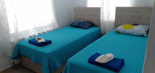 two twin beds with hats and towels on them at GEYİKLİ BULUT Pansiyon in Ezine