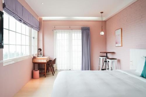 una camera con letto, scrivania e finestra di Canaan B&B Kenting a Eluan