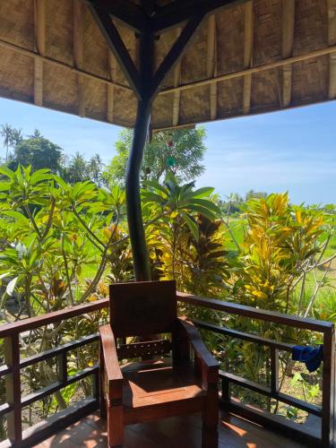 a wooden bench sitting on a balcony with trees at Pondok Punaga in Jasri