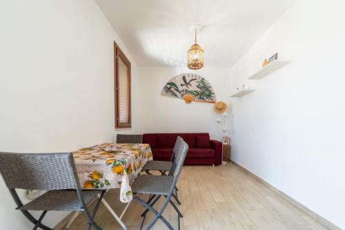 a dining room with a table and chairs and a red couch at Home BellaVista, a pochi passi dalla spiaggia in Favignana