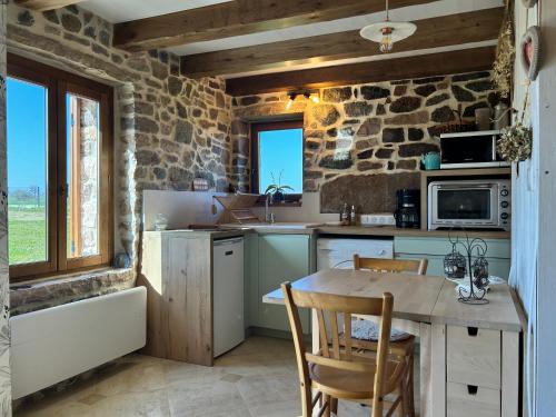 une cuisine avec une table et des chaises et un mur en pierre dans l'établissement 206 - Charmante maison bretonne idéale pour deux., à Plurien