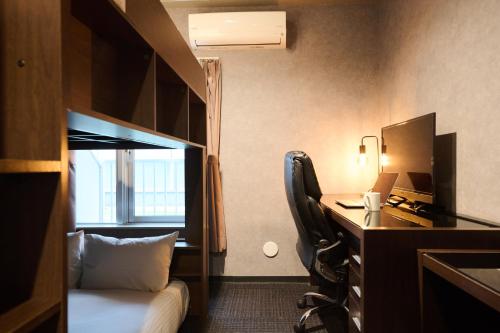 a hotel room with a desk with a computer and a bed at Residence Hotel Stripe Sapporo in Sapporo