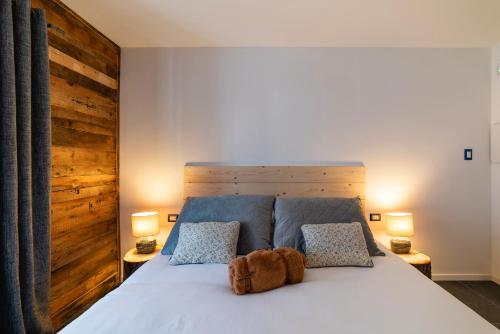a teddy bear sitting on a bed with two lamps at Lussari Style Apartments in Camporosso in Valcanale
