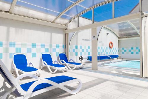 a room with chairs and a swimming pool at Résidence Odalys Les Villas de la Baie in Le Crotoy