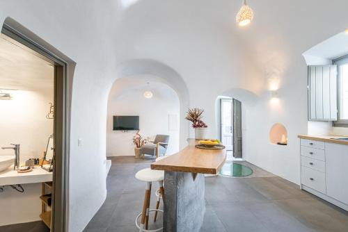 cocina y sala de estar con paredes blancas y mesa en Veneston Suites, en Fira