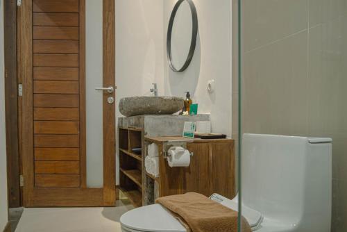 a bathroom with a sink and a toilet and a mirror at MIMOYA Guest House, Sanur in Sanur