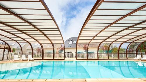 - une grande piscine avec un grand bâtiment doté de fenêtres dans l'établissement Vacancéole - Le Domaine de la Corniche - Deauville Sud, à Auberville