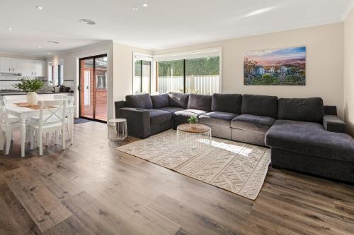 a living room with a couch and a table at Summery 4BR Home by Mel Airport, CBD & Watergardens in Sydenham