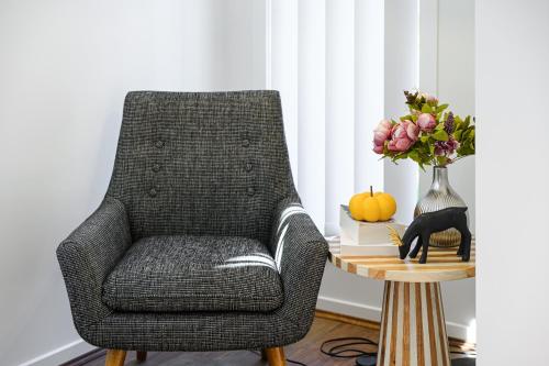 a chair sitting next to a table with a vase of flowers at Austral 5B3B 10 Guests Near Train & Shops in Austral