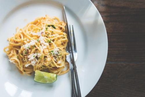 a plate of pasta with a fork and a lime at The Ship Inn in Mousehole