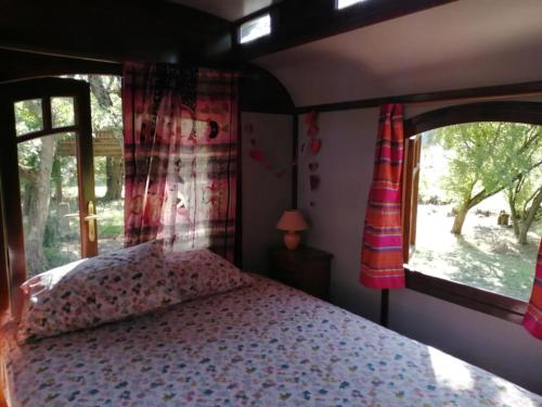 a bedroom with a bed and a window at La Roulotte Authentique in Grignan